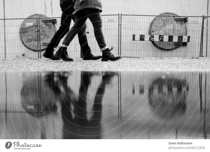 Spiegelung von Beinen vor einer Baustelle Reflexion & Spiegelung Wasser Spiegelung im Wasser Außenaufnahme Mann spiegeln Wasseroberfläche gehen schwarzweiß