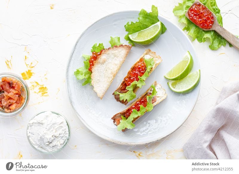 Leckere Kaviar-Tacos auf Holzbrett auf Tisch Amuse-Gueule Lachs mexikanisches Essen dienen Küche Tortilla Tradition geschmackvoll frisch Gastronomie