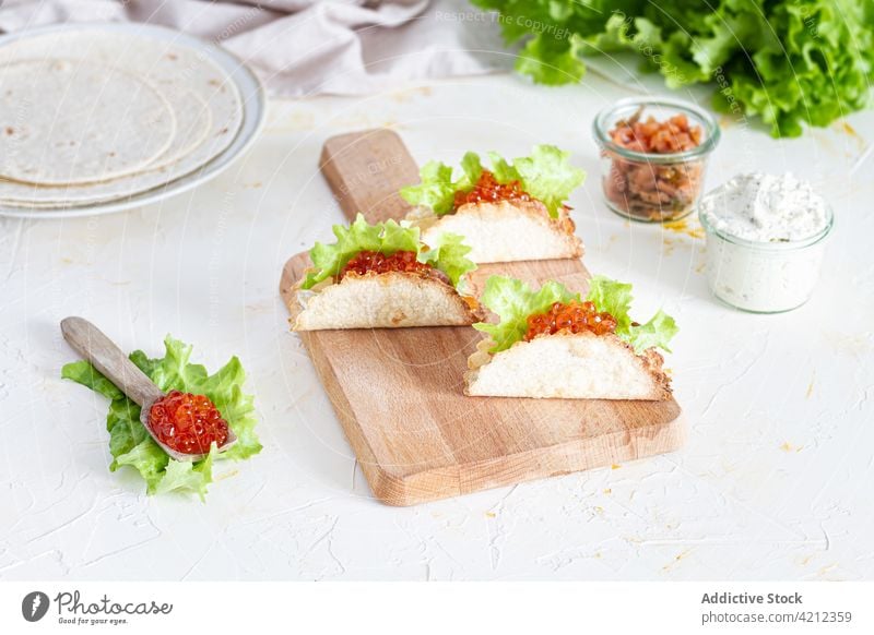 Leckere Kaviar-Tacos auf Holzbrett auf Tisch Amuse-Gueule Lachs mexikanisches Essen dienen Küche Tortilla Tradition geschmackvoll frisch Gastronomie