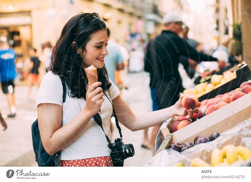 Junge touristische Frau isst ein Eis und kauft einige Früchte in einem Straßenmarkt Tourist kaufen Markt Lebensmittelgeschäft Frucht Urlaub reisen Feiertag