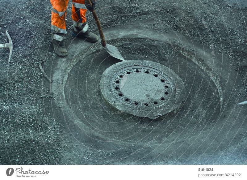 Straßenbauarbeiter mit orangener Hose und Schaufel strassenarbeiter schaufel hose reflektierend arbeiten stemmarbeiten kanaldeckel manhole asphaltarbeiten