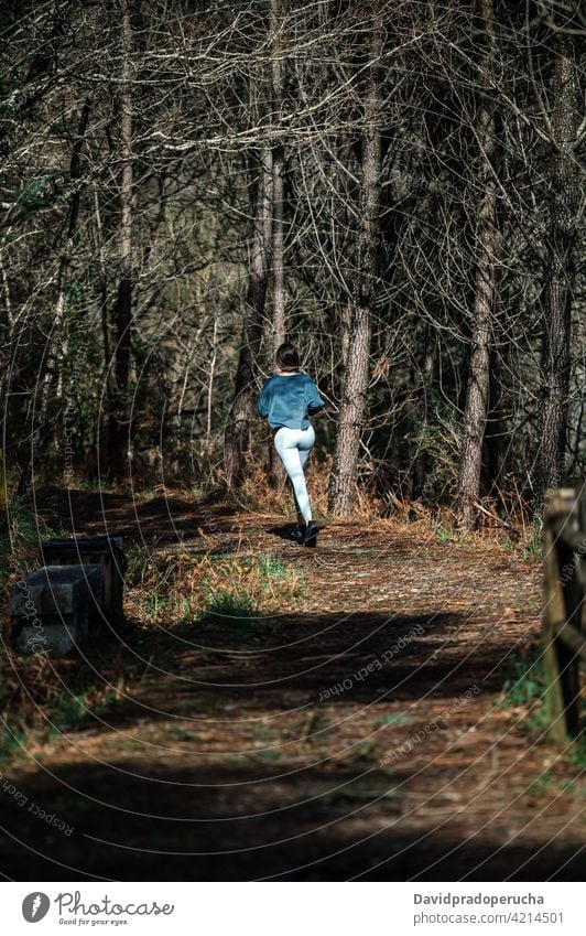 Sportliche Frau läuft im Wald laufen sportlich aktiv Training Fitness Sportkleidung passen Wälder Aktivität Läufer Sportlerin joggen Gesundheit Weg Nachlauf