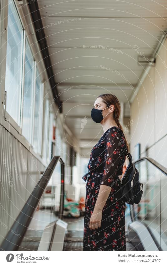 Frau mit Gesichtsmaske auf fahrender Rolltreppe stehend Erwachsener attraktiv schön Schönheit Business lässig Kaukasier Großstadt Coronavirus Bund 19 Eingang