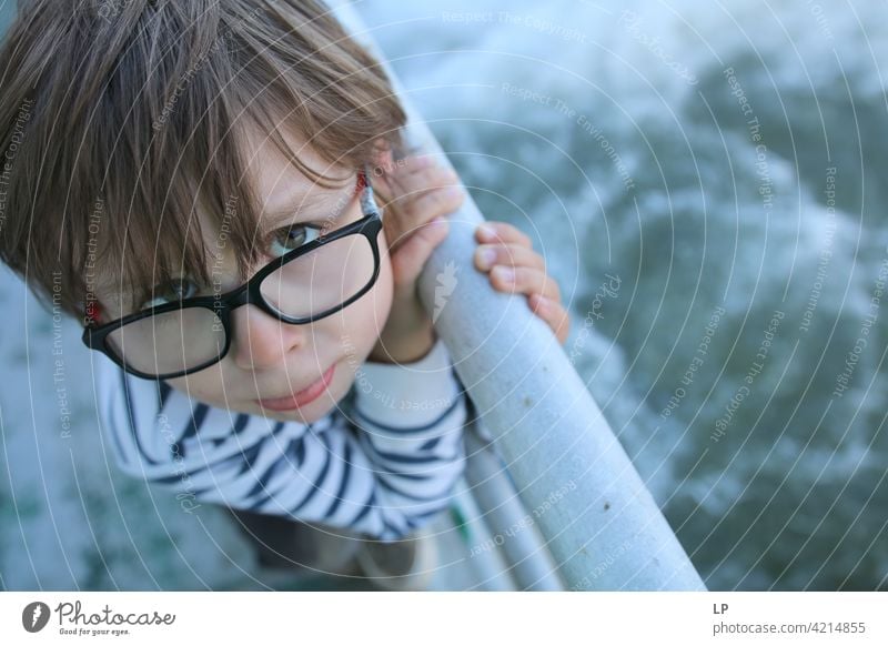 Kind mit Brille, das ein nach oben schauendes Gesicht macht zögernd verwirrt ratlos skeptisch Zweifel zweifelhaft hestitate Unsicherheit Verwirrung Kindheit