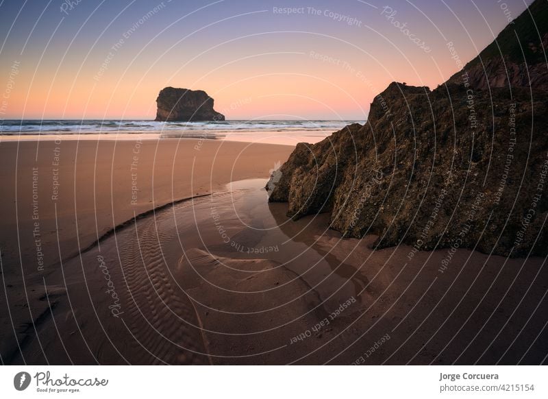 Wasserpfütze in Form eines Pferdekopfes bei Sonnenuntergang am Strand von Ballota, Asturien.  Spanien. Atemberaubende Farben dramatischer Himmel