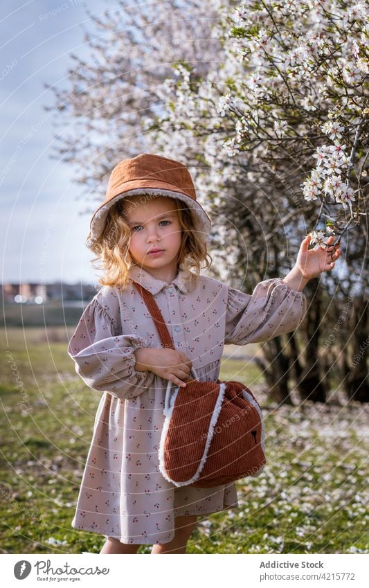 Nettes Mädchen in blühendem Frühlingsgarten stehend Garten Blütezeit Baum niedlich Kind Blume Park Natur bezaubernd Kindheit charmant Hut Kleid unschuldig