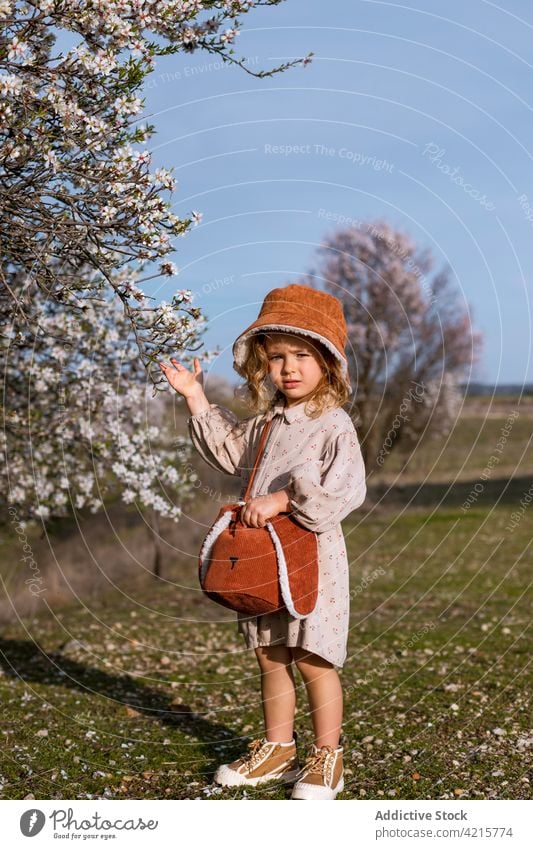 Nettes Mädchen in blühendem Frühlingsgarten stehend Garten Blütezeit Baum niedlich Kind Blume Park Natur bezaubernd Kindheit charmant Hut Kleid unschuldig