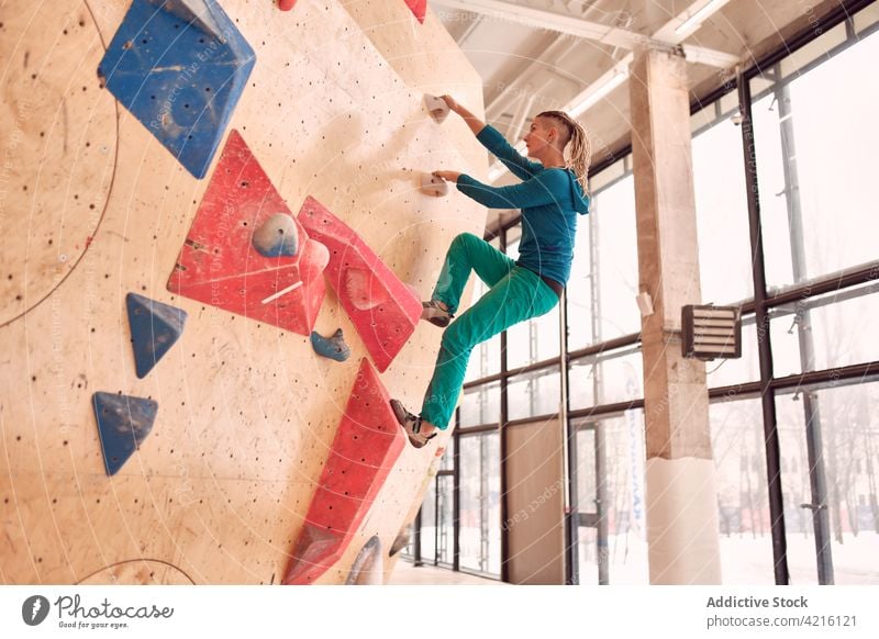 Kletterin klettert in einer Boulderhalle die Wand hoch Sportlerin Aufstieg Felsbrocken hängen Aufsteiger Training Bergsteiger Alpinist stark Frau Übung