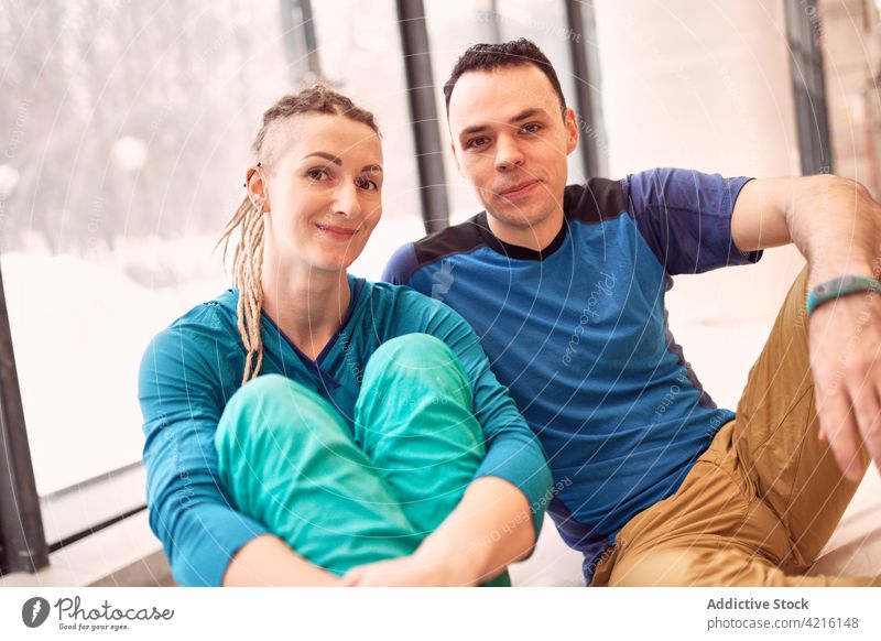 Lächelnde Kletterer in der modernen Boulderhalle Sportlerin Aufsteiger Zentrum Felsbrocken Athlet Aufstieg Wand künstlich heiter Fitnessstudio sitzen Stock