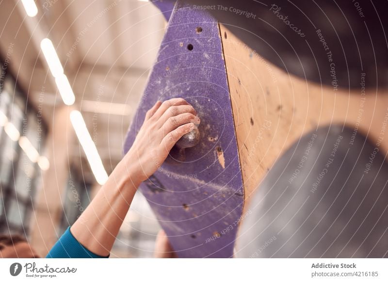 Crop Woman Kletterwand im Bouldering Center Aufsteiger Wand Felsbrocken Aufstieg hängen Sportlerin Bergsteiger Alpinist Übung Gleichgewicht Frau Training stark