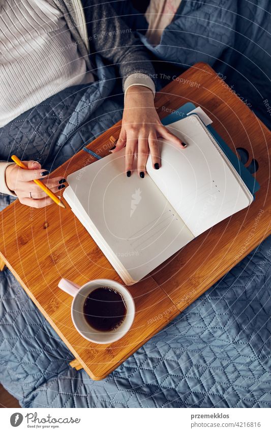 Schüler lernen zu Hause. Junge Frau macht Notizen, Lesen und Lernen von Notizblock. Mädchen schreiben Journal sitzen im Bett Bildung im Innenbereich arbeiten