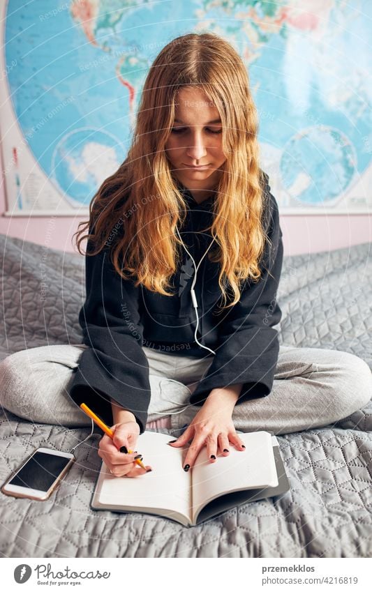 Schüler beim Lernen zu Hause. Junge Frau macht sich Notizen, liest und lernt vom Notizblock Bildung im Innenbereich arbeiten Person Hinweis Notebook studierend