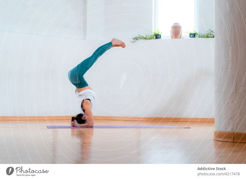 Unerkennbare Frau, die einen gestützten Kopfstand mit Spagat im Zimmer ausführt angehobene Beine Gleichgewicht Yoga Umkehrung Talent Fähigkeit üben Haus perfekt