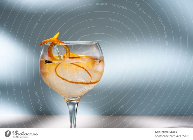 Glas Gin Tonic mit Orangenzesten auf dem Tisch Cocktail Alkohol hochball orange Schale Gewürznelke Schatten Wittern hell kreativ Design Wasser Aroma