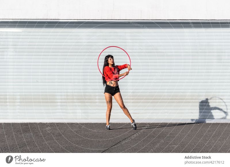 Tänzerin dreht Hula-Hoop-Reifen auf dem Bürgersteig spinnen Tanzen aktiv passen Tattoo Frau herumwirbeln Bewegung Choreographie Schatten Körper selbstbewusst