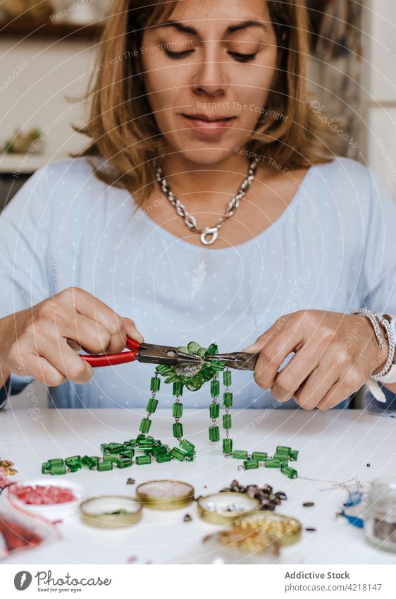 Frau macht Accessoire mit Natursteinen Kunstgewerbler Halskette Fähigkeit Instrument Werkstatt dekorieren schmücken kreieren Prozess Designer Bijouterie Zange