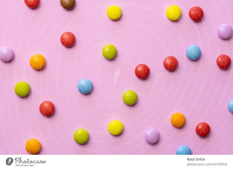 Bunte Schokolade Bonbons smarties background.top view Süßigkeiten mehrfarbige Lebensmittel Textur, auf rosa Hintergrund. farbenfroh Smarties Konditorei Bälle