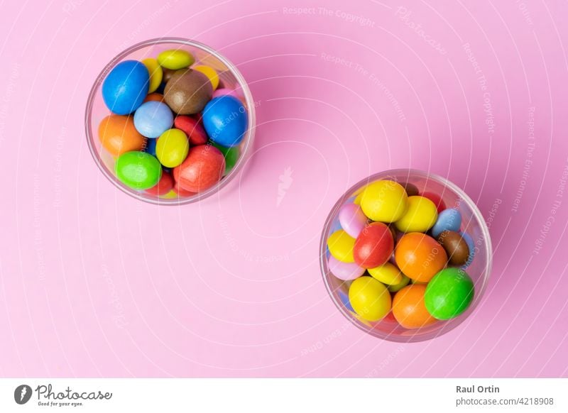 Mehrfarbige Schokolade Bonbons im Glas Glas auf blauem Vintage-Holz background.Top Ansicht bunte Süßigkeiten Hintergrund Konzept mit Kopie Raum für Text.