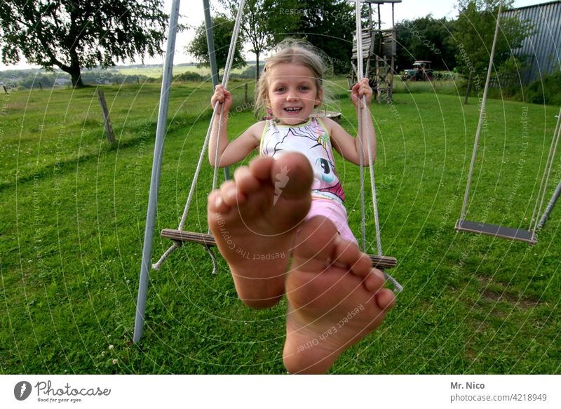 Mädchen schaukelt barfuß im Garten schaukeln Kleinkind Kindheit Spielen Schaukel Spielplatz Bewegung Lebensfreude spass lächeln lachen Schwung Sommer Glück Spaß