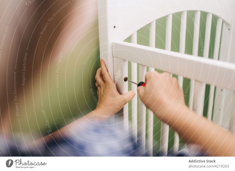 Frau beim Zusammenbau eines Kinderbettes in einem hellen Haus versammeln Babybett Schraubendreher Reittier Arbeit Werkzeug Raum gerippt Möbel achtsam heimwärts