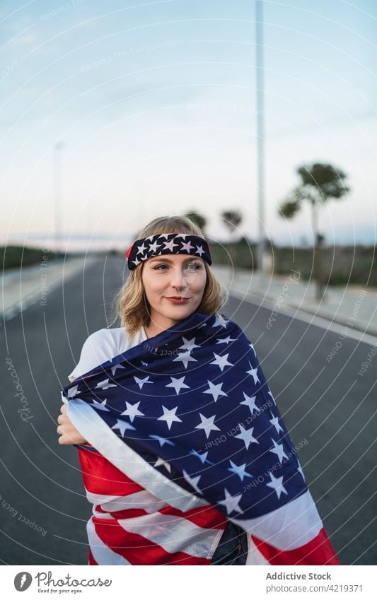 Zufriedene Frau mit USA-Flagge auf der Straße stehend Fahne Patriotin sorgenfrei Inhalt Freiheit national Sonnenuntergang Symbol Amerikaner eingewickelt amerika