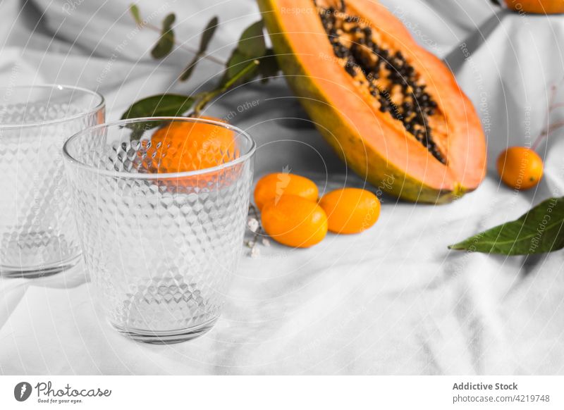 Papaya zwischen Mandarinen und Kumquats auf geknittertem Stoff schneiden Frucht tropisch natürlich frisch Vitamin Blatt Gewebe geschnitten Hälfte Samen reif