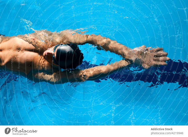 Sportler mit Schwimmbrille schwimmt während des Trainings im Pool Schwimmer schwimmen Arme hochgezogen Übung üben Mann Motivation Energie Stärke maskulin