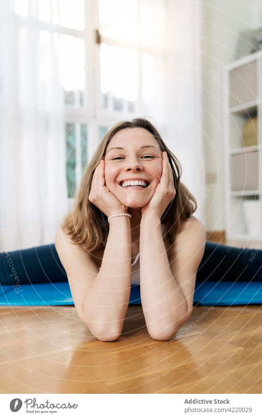 Zufriedene Frau in geteilter Yogapose sitzend und in die Kamera schauend Split üben Dehnung beweglich Asana heimwärts Pose Lächeln heiter Harmonie passen Inhalt