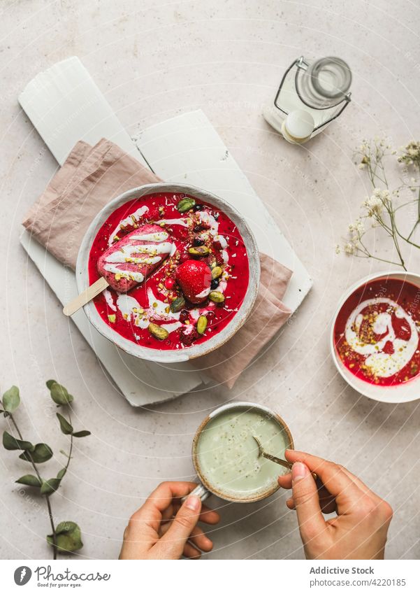 Person mit kalter Beerensuppe und Matcha-Tee Suppe süß Dessert Schalen & Schüsseln Tasse rühren frisch Getränk trinken lecker geschmackvoll organisch natürlich