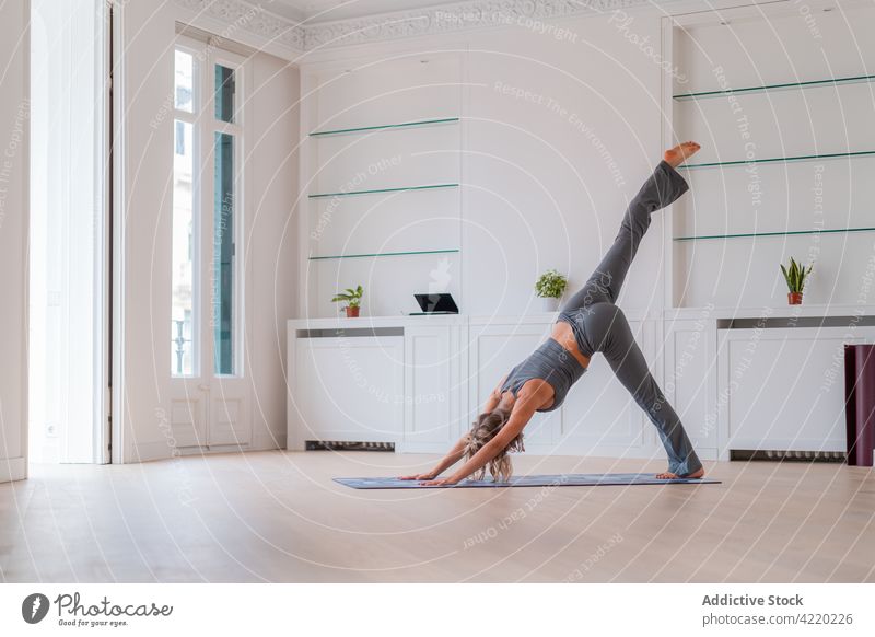 Gelassene Frau beim Yoga im dreibeinigen nach unten gerichteten Hund Gleichgewicht Pose Achtsamkeit Zen nach unten gerichteter Hund heimwärts üben Harmonie