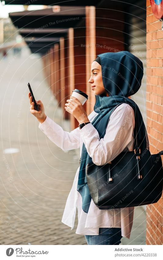 Muslimische Frau, die sich auf dem Bahnhof mit ihrem Smartphone fotografiert Selfie Hijab warten klug Selbstportrait Imbissbude trinken ethnisch muslimisch