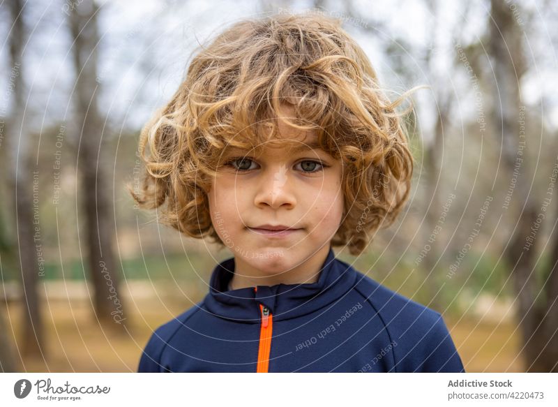 Junge in Sportkleidung mit gewelltem Haar bei Tag charmant freundlich Kindheit herzlich wehmütig lässig Stil allein Porträt Kapuzenpulli grau weich anhaben