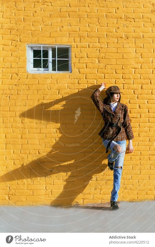 Trendiges Modell in zerrissenen Jeans lehnt sich an eine bemalte Ziegelwand Stil Individualität Bein angehoben Backsteinwand Schatten Frau Straße Straßenbelag