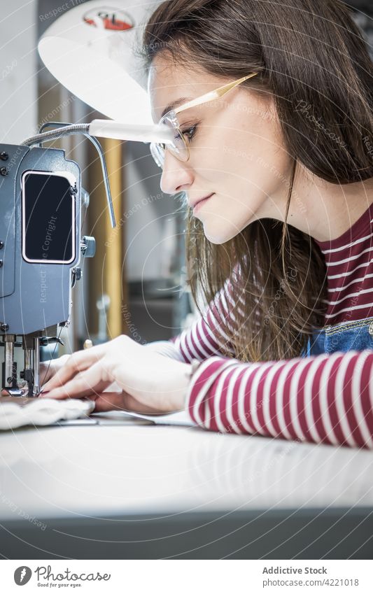 Näherin beim Nähen an der Nähmaschine in der Werkstatt Abwasserkanal Frau nähen Polsterung Stoff Material Hobelbank Handwerkerin Design professionell Arbeit