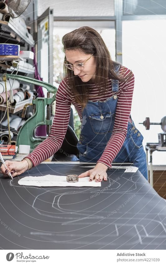 Frau arbeitet mit Leder in einer Werkstatt Mark Gewebe Polsterung Hobelbank Arbeit handgefertigt Abwasserkanal Handwerkerin Material kreieren Kunstgewerbler