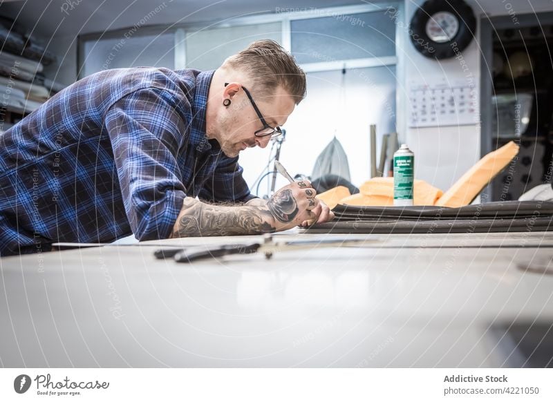 Handwerker markiert Leder an der Werkbank Kunsthandwerker Werkstatt Mark Gewebe Kunstgewerbler Schreibstift Polsterung kreieren Hobelbank männlich Mann Stoff