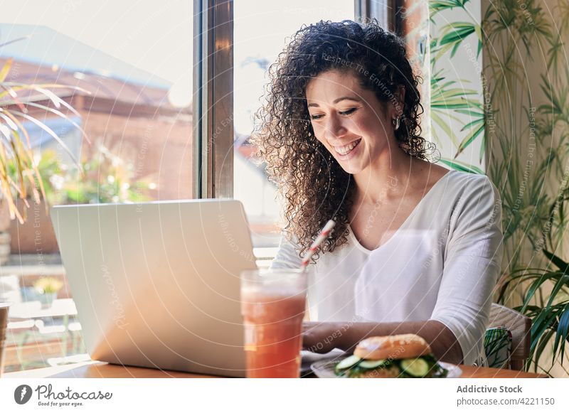 Ethnische Fernarbeiterin tippt beim Frühstück im Restaurant auf einem Laptop Mitarbeiter Tippen freiberuflich Brunch Glück Belegtes Brot trinken Frau benutzend