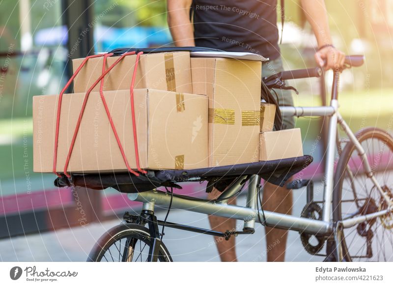 Fahrradkurier bei einer Lieferung Menschen junger Erwachsener Mann männlich Lächeln Glück blauer Kragen Kurier Meldereiter Auslieferer Versand liefernd Paket