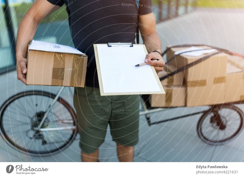 Kurier mit Klemmbrett und Kartons Menschen junger Erwachsener Mann männlich Lächeln Glück blauer Kragen Meldereiter Auslieferer Versand liefernd Paket Pakete