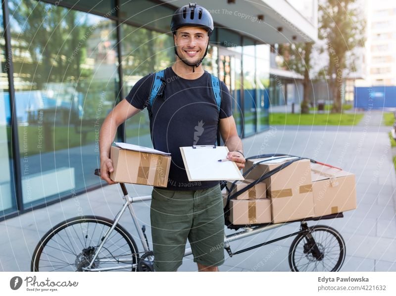 Fahrradkurier, der eine Lieferung auf einem Lastenfahrrad macht Menschen junger Erwachsener Mann männlich Lächeln Glück blauer Kragen Kurier Meldereiter