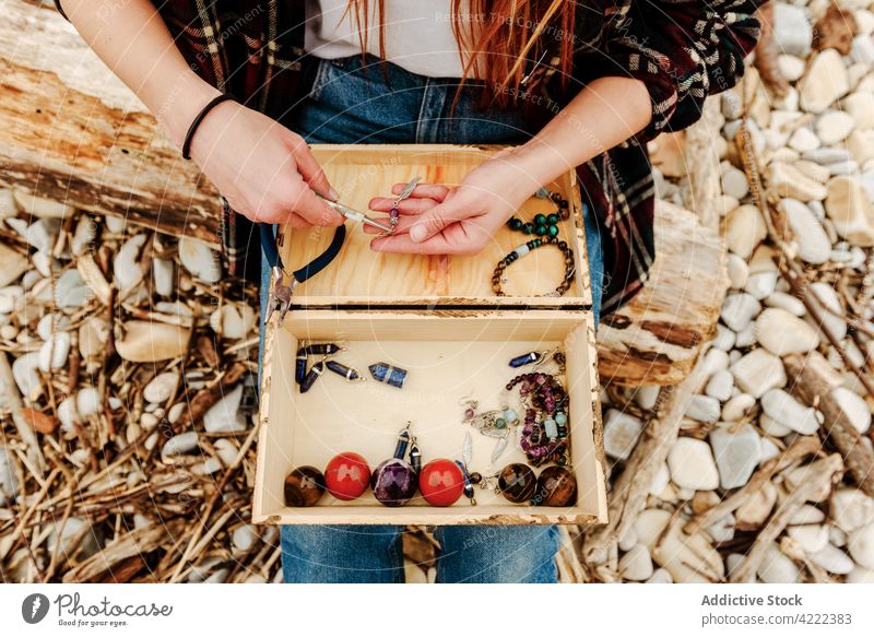 Crop-Frau kreiert Accessoires am Meer Handwerkerin kreieren Bijouterie halbedel Stein kreativ Hobby Kunstgewerbler natürlich sitzen Strand Seeküste Meeresufer