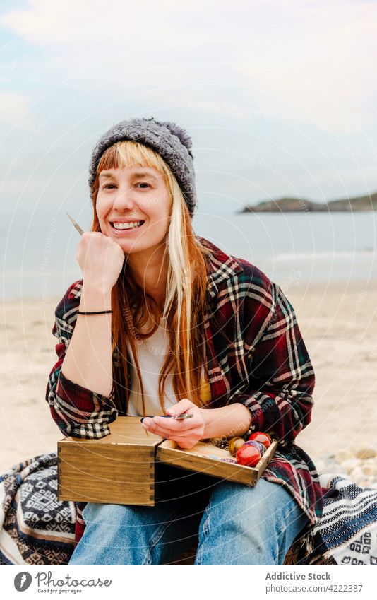 Frau kreiert Accessoires am Meer Handwerkerin kreieren Lächeln Bijouterie kreativ Glück Hobby Kunstgewerbler natürlich Form sitzen Strand Seeküste Meeresufer