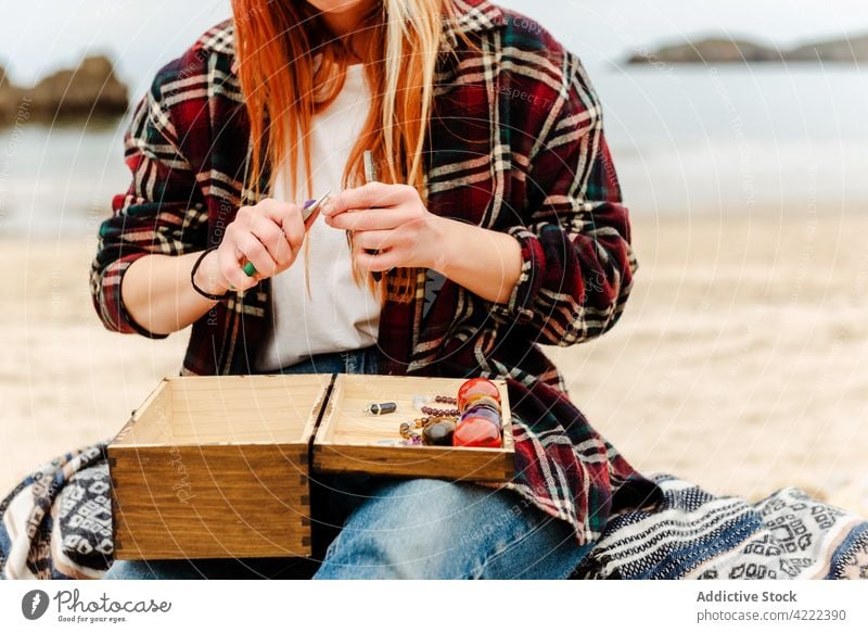 Crop-Frau kreiert Accessoires am Meer Handwerkerin kreieren Bijouterie halbedel Stein kreativ Hobby Kunstgewerbler natürlich Form sitzen Strand Seeküste