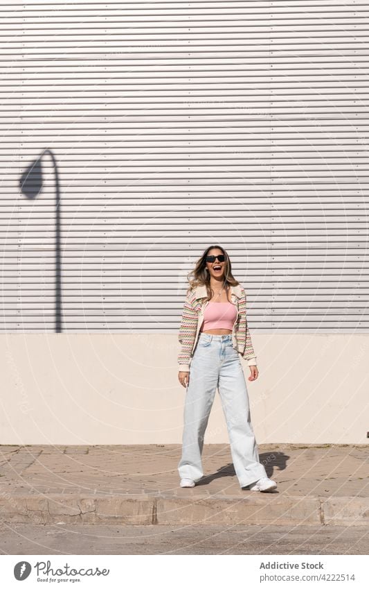 Trendy Frau lachend auf städtischen Bürgersteig im Sonnenlicht Stil Mode Individualität Lachen Spaß haben sorgenfrei tausendjährig Straßenbelag urban positiv