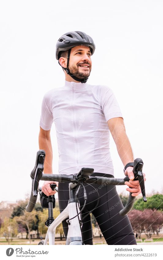 Bärtiger Radfahrer mit Fahrrad unter weißem Himmel Sport maskulin Macho viril selbstbewusst Stil Mann professionell Verkehr Fahrzeug Schutzhelm modern Sportler