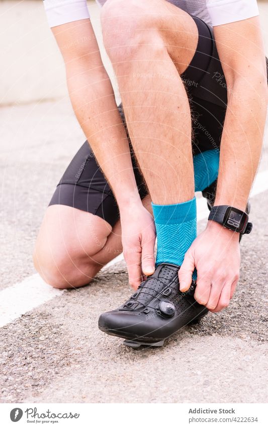 Crop Biker in Sportkleidung auf städtischer Straße gegen Fahrrad Radfahrer Fahrradfahren Schuh modern Stil Mann urban Kniebeuge Großstadt Kniestrümpfe