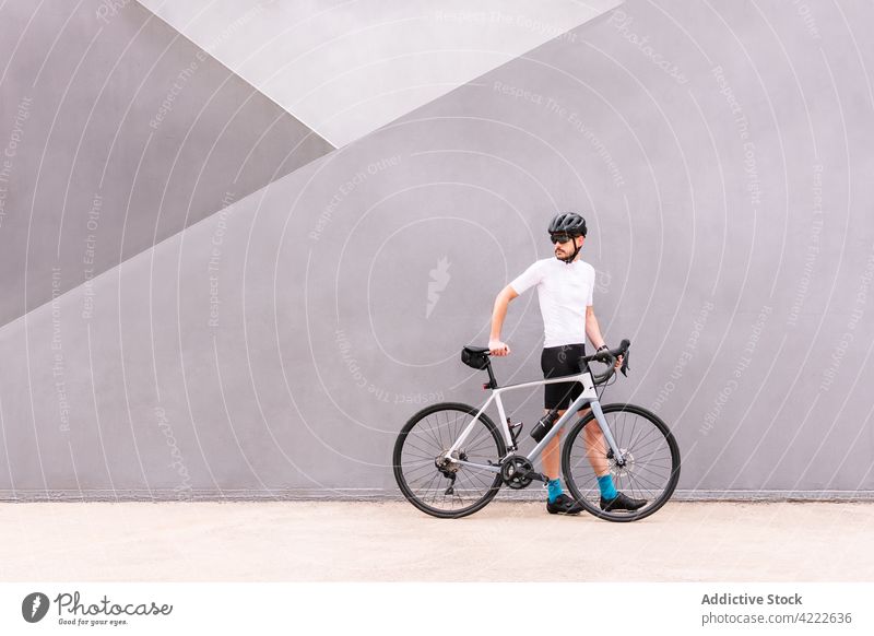 Radfahrer mit Fahrrad auf städtischem Bürgersteig Sport professionell Stil maskulin Spaziergang Straßenbelag urban Mann Verkehr Fahrzeug Kniestrümpfe Schutzhelm