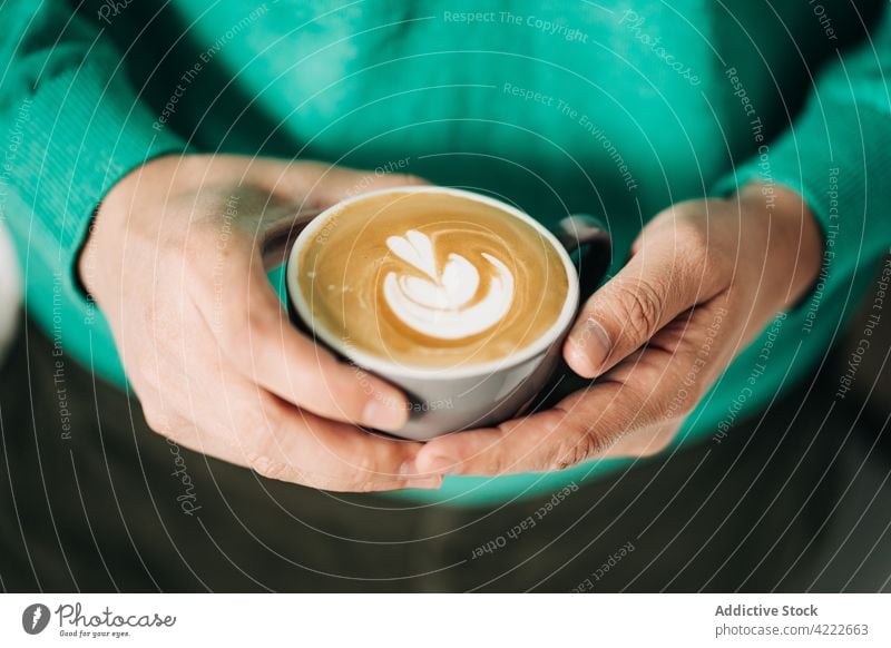 Crop-Person mit einer Tasse leckerem Milchkaffee Latte Kaffee Latte Art Heißgetränk Getränk melken Aroma natürlich frisch Keramik Material Bierschaum Molkerei