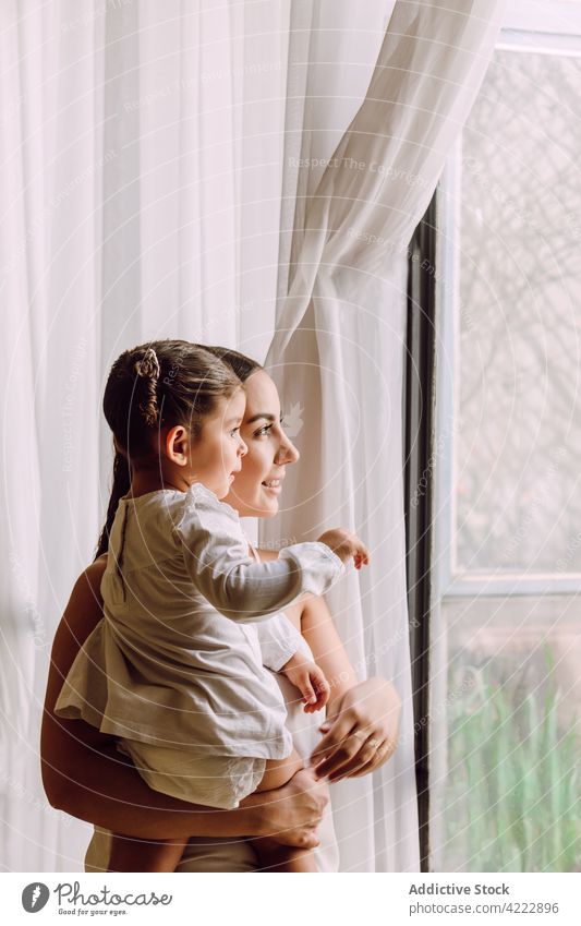 Frau mit kleinem Kind schaut aus dem Fenster Mutter heimwärts wenig Eltern Tochter neugierig interessant Zusammensein ethnisch zu Hause Mädchen Mama bezaubernd