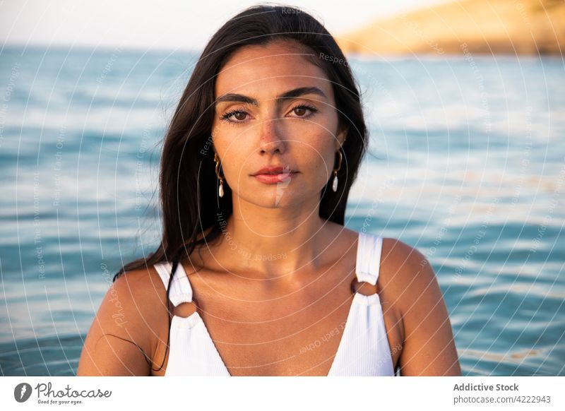 Modell im Badeanzug am Strand gegen das Meer MEER Körper Badebekleidung feminin selbstbewusst Meereslandschaft Frau Porträt Blauer Himmel sandig Natur wolkig